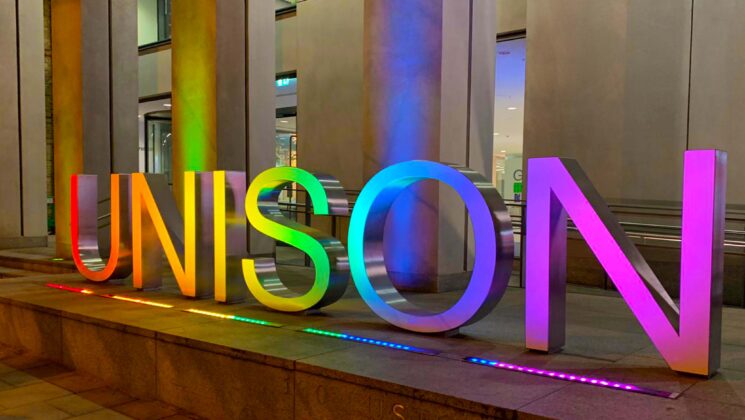 UNISON logo lit up in pride flag colours outside UNISON centre in London.