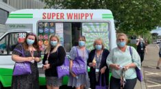 NHS workers hold purple UNISON tote bags while enjoying an ice cream. An ice cream van can be seen in the background.