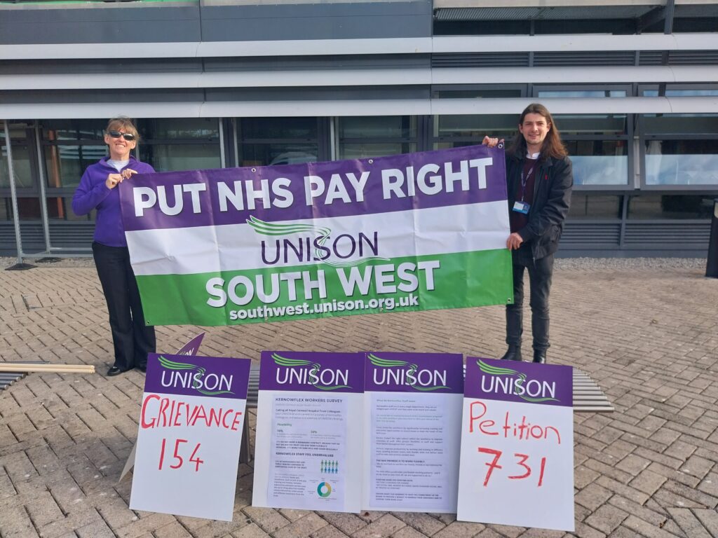 UNISON reps hold 'put NHS pay right' banner with placards about petition signatories are in the foreground.