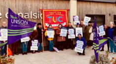 UNISON members lobby council meeting. They hold flags and placards.