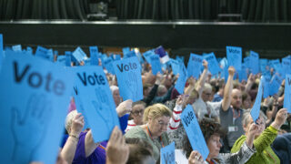 Delegates at UNISON's national delegate conference hold voting cards aloft.