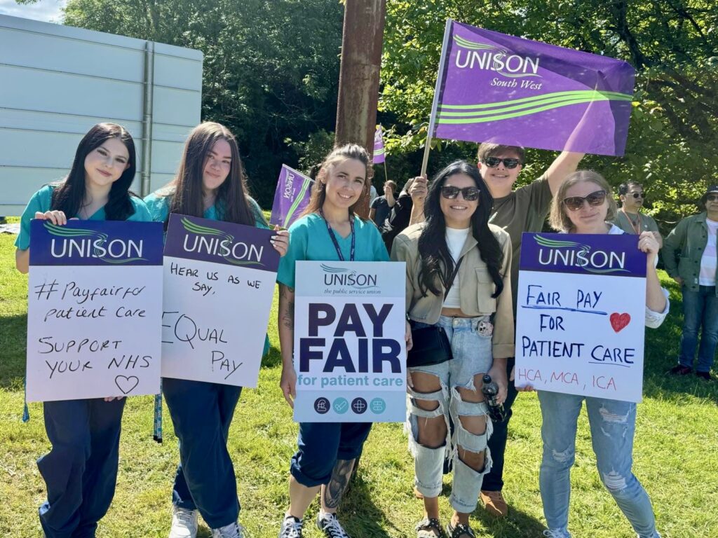 Group photo of healthcare workers holding placards and UNISON flags. The placards read 'pay fair for patient care' and 'hear us as we say... equal pay!"