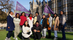 Migrant workers hold UNISON flags in a staged photo outside the Houses of Parliament.