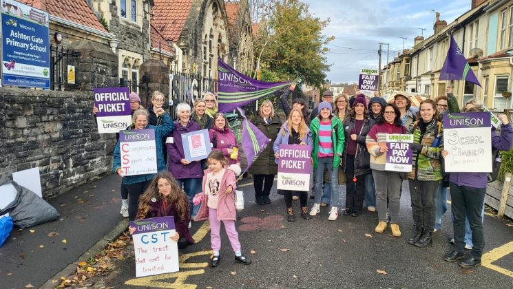 Staff on the picket line outside Ashton Gate Primary School holding placards and UNISON flags.