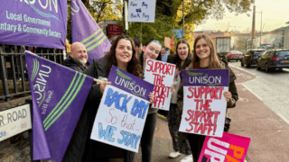 Staff on the picket line outside Cathedral Primary School holding placards and UNISON flags.