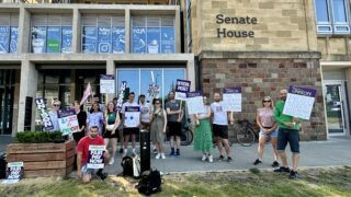 University workers picketing outside Senate House in Bristol, the sun is shining and they're holding UNISON placards with a variety of slogans about fair pay.
