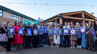 One Weekend participants pose for a photo with a sign reading 'fair visas now'